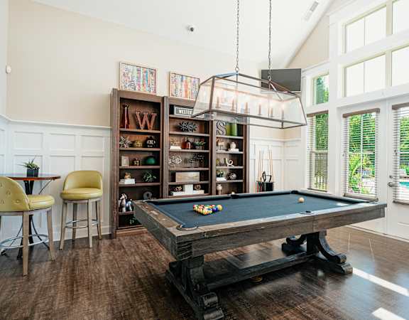 a pool table in a living room with a light hanging over it