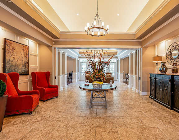 a lobby with red chairs and a table and a chandelier