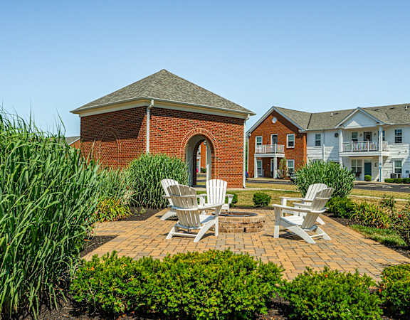 a brick patio with two chairs and a fire pit in front of a brick building