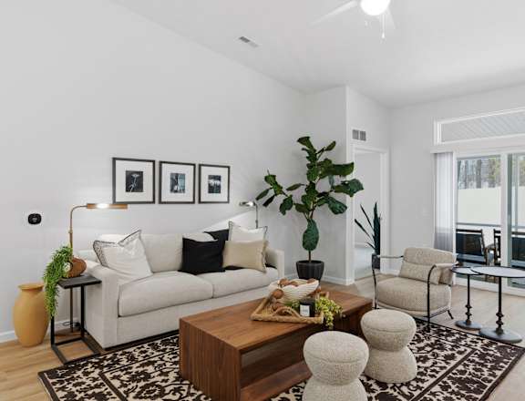 A living room with a white couch, a coffee table, and a large window.