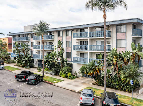A building with balconies and palm trees in front.