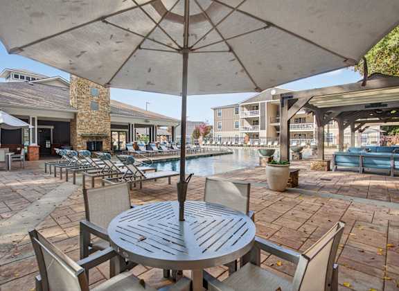 A patio with a table and chairs under an umbrella.