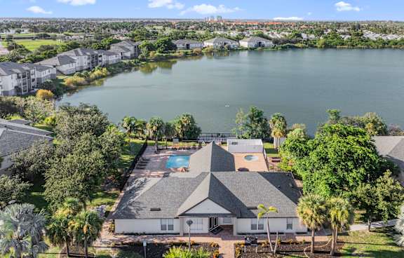 A large house with a pool in the middle of a lake surrounded by trees. at Cascades at Clear Lake Apartments, Ft. Myers, Florida