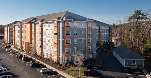A large apartment building with a parking lot in front.