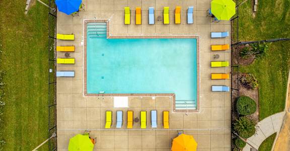 An aerial view of a swimming pool surrounded by sun loungers and umbrellas.