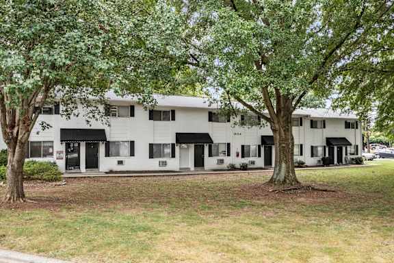 A white building with black awnings is surrounded by trees.