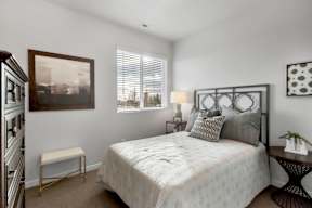 A bedroom with a large bed, a small table, and a painting on the wall.
