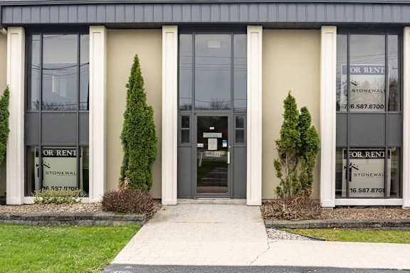 the front of a building with glass doors and a sidewalk