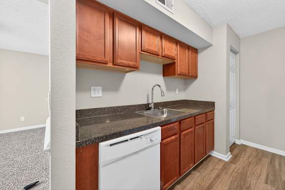 A kitchen with brown cabinets and a white dishwasher.
