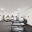A gym with a variety of equipment including treadmills, stationary bikes, and weight machines.