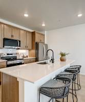 A kitchen with a white countertop and black chairs.