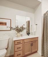 A bathroom with a white toilet, a sink with a mirror, a plant, and a shower curtain.