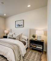 A bedroom with a large bed and a window with blinds.