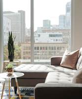1-Bedroom Apartments in Pearl District, Portland, OR - Couch9 - Living Room with Area Rug, Sectional Couch, Coffee Tables, and Floor-to-Ceiling Windows.