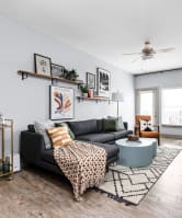 living room with a couch and coffee table with a kitchen in the background at the vue apartments in indianapolis