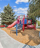 A playground with a red slide and a red bench.