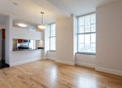 Thumbnail 18 of 23 - A large empty room with wooden floors and a window with blinds.
