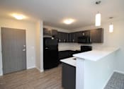 Thumbnail 1 of 14 - A kitchen with black appliances and brown cabinets.