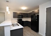 Thumbnail 7 of 14 - A kitchen with black appliances and a white counter.