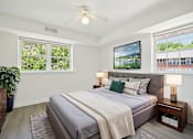 Thumbnail 4 of 8 - A bedroom with a bed, a ceiling fan, and a large window.