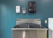Thumbnail 24 of 26 - A sink with a soap dispenser and hand dryer on a wall. at AVIA Lofts on Victors Way, Ann Arbor, 48108