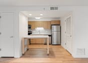 Thumbnail 19 of 29 - A kitchen with wooden cabinets and a white island. at AVIA Lofts on Parkway, Vancouver