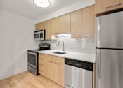 Thumbnail 1 of 29 - A kitchen with wooden cabinets and stainless steel appliances. at AVIA Lofts on Parkway, Washington , 98662