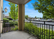 Thumbnail 16 of 17 - A view from a balcony looking out at a street with cars and trees.