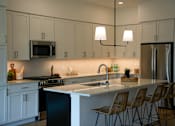 Thumbnail 7 of 8 - A kitchen with white cabinets and a black dishwasher.