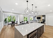 Thumbnail 4 of 22 - A modern kitchen with a large island and pendant lights.