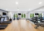 Thumbnail 3 of 22 - A spacious gym with treadmills, elliptical machines, and other exercise equipment.