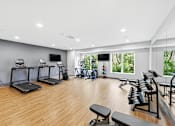 Thumbnail 6 of 22 - A well-lit gym with treadmills, exercise bikes, and weight benches.