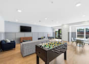 Thumbnail 8 of 22 - A game room with a foosball table and a couch.