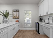 Thumbnail 2 of 30 - A kitchen with white cabinets and a wooden floor.