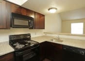 Thumbnail 23 of 36 - Kitchen with black appliances including microwave and wrap around light grey countertops
