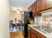 Thumbnail 1 of 36 - Spacious modern kitchen with black appliances, decorative pottery on light grey countertops and large on basin sink