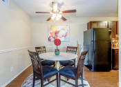 Thumbnail 31 of 36 - dining room with dark wood panel flooring and a round light colored table and ceiling fan and black appliances in view