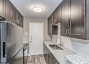 Thumbnail 14 of 31 - Kitchen with dark cabinets and granite-style countertops at Chapel Creek Apartments Dallas