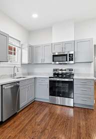 A modern kitchen with stainless steel appliances and wooden floors.