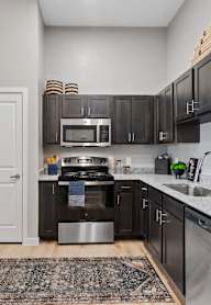 A kitchen with a refrigerator, microwave, and oven.