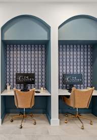 Three desks with chairs are in a room with arched windows.
