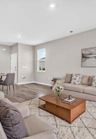 A living room with a grey couch, a coffee table, and a painting on the wall.