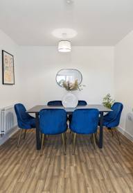 a dining room with a wooden table and blue chairs and a blue wall with artwork