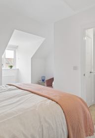 a bedroom with a bed and a nightstand with a lamp and a framed picture