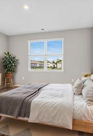 A bedroom with a large bed, a television, and a window with a view of the outdoors.