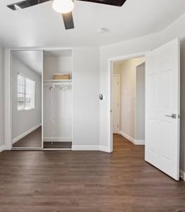 A room with a ceiling fan and a large mirror.