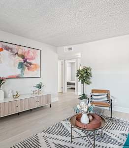A living room with a green couch and a painting on the wall.