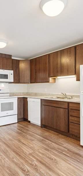 A kitchen with white appliances and wooden cabinets.