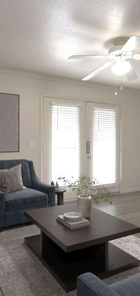 A living room with a grey couch, a blue chair, a coffee table, and a flat screen TV mounted on the wall.