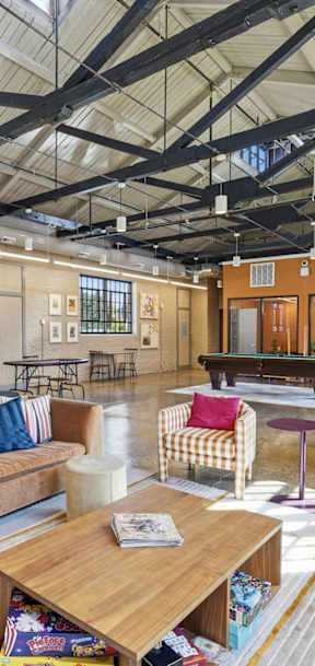 A large, open-plan living area with a variety of seating options and a high ceiling with exposed beams.